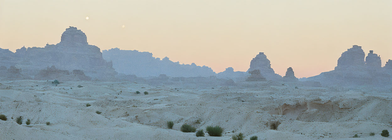 Desert landscape at dusk with rock formations and moon