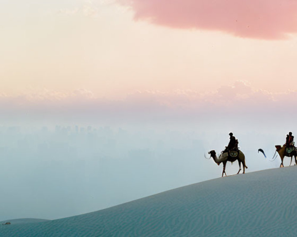 Desert sunrise with silhouetted figures on camels and distant city haze.