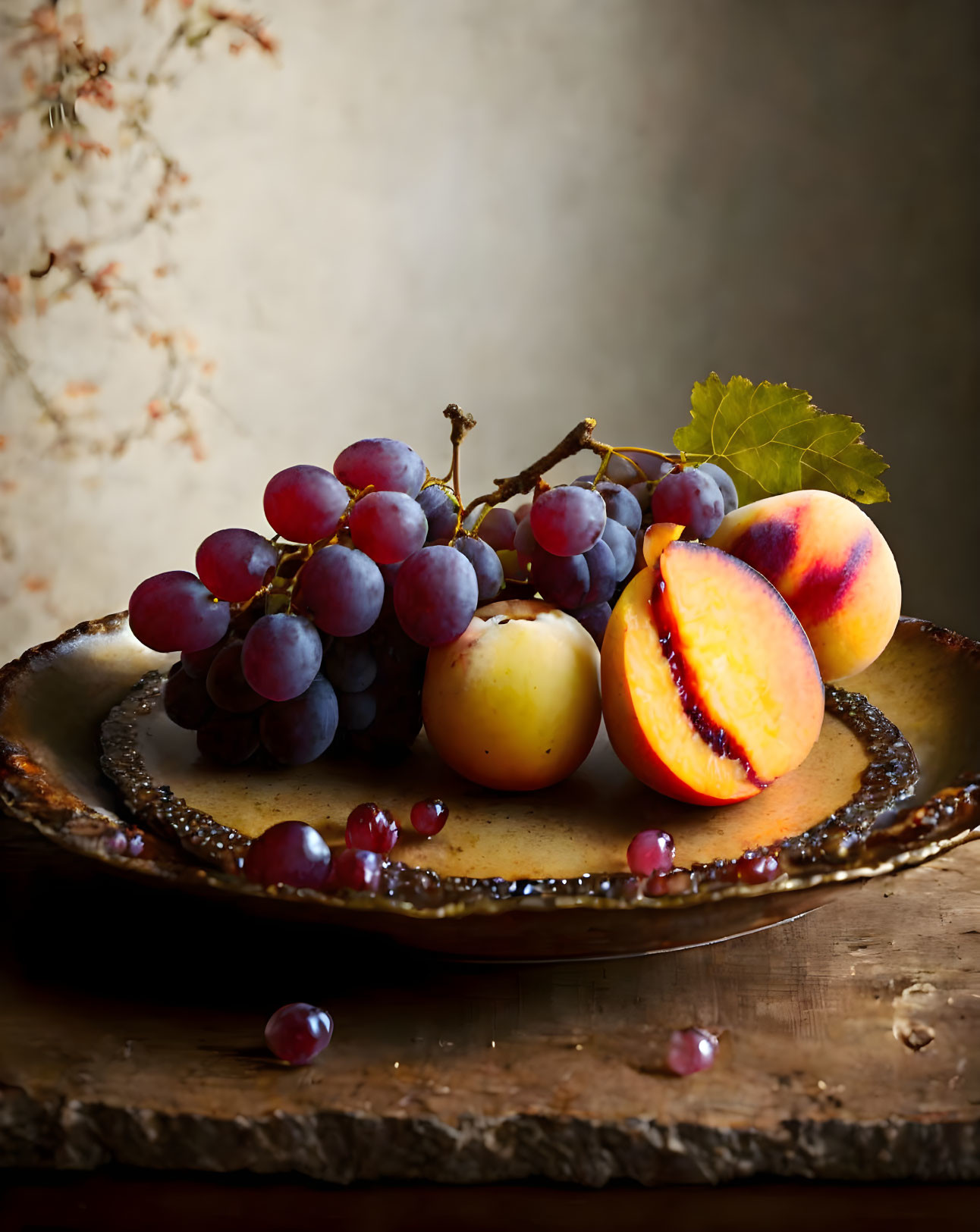 Rustic plate with red grapes, white apricots, and cut peach on textured backdrop