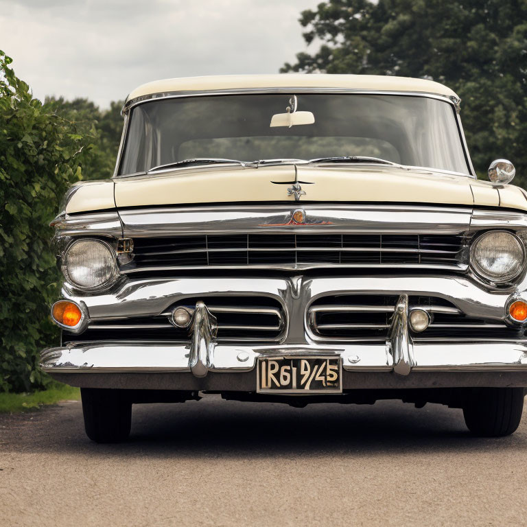 Classic two-tone sedan with chrome details and white-wall tires on road with trees