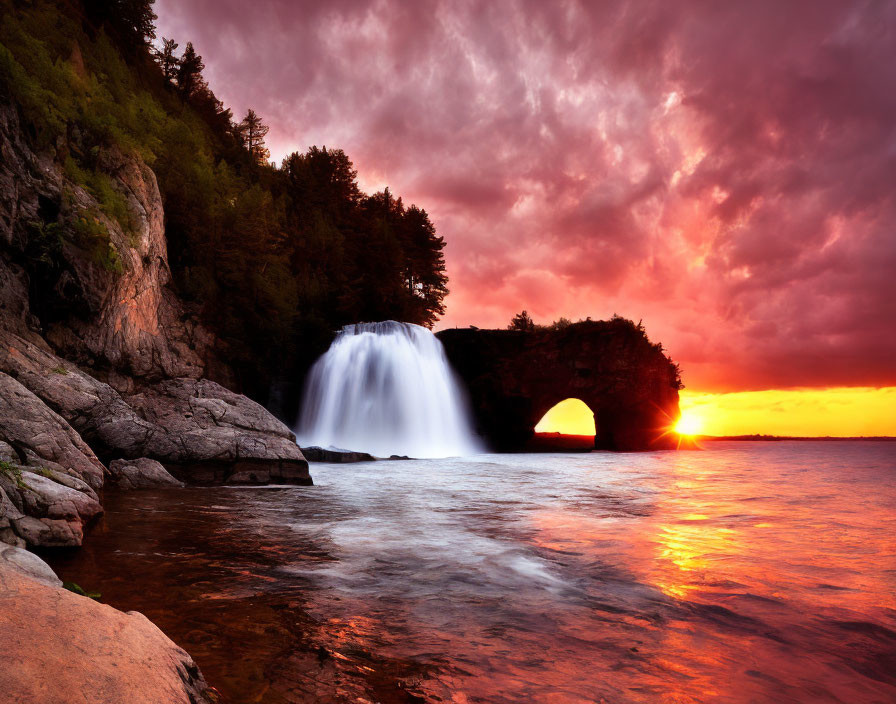 Tranquil lake sunset with waterfall and natural arch under orange and purple sky