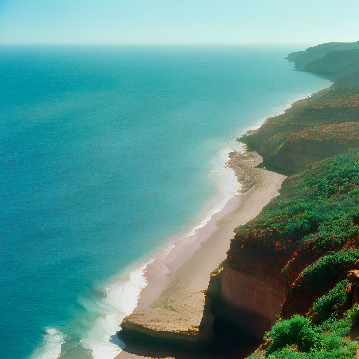 Aerial View of Coastline with Steep Cliffs and Sandy Beach