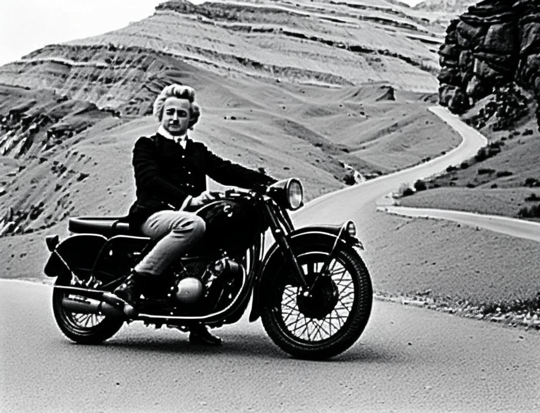 Person with Mohawk Hairstyle Riding Classic Motorcycle on Winding Mountain Road in Black & White Photo