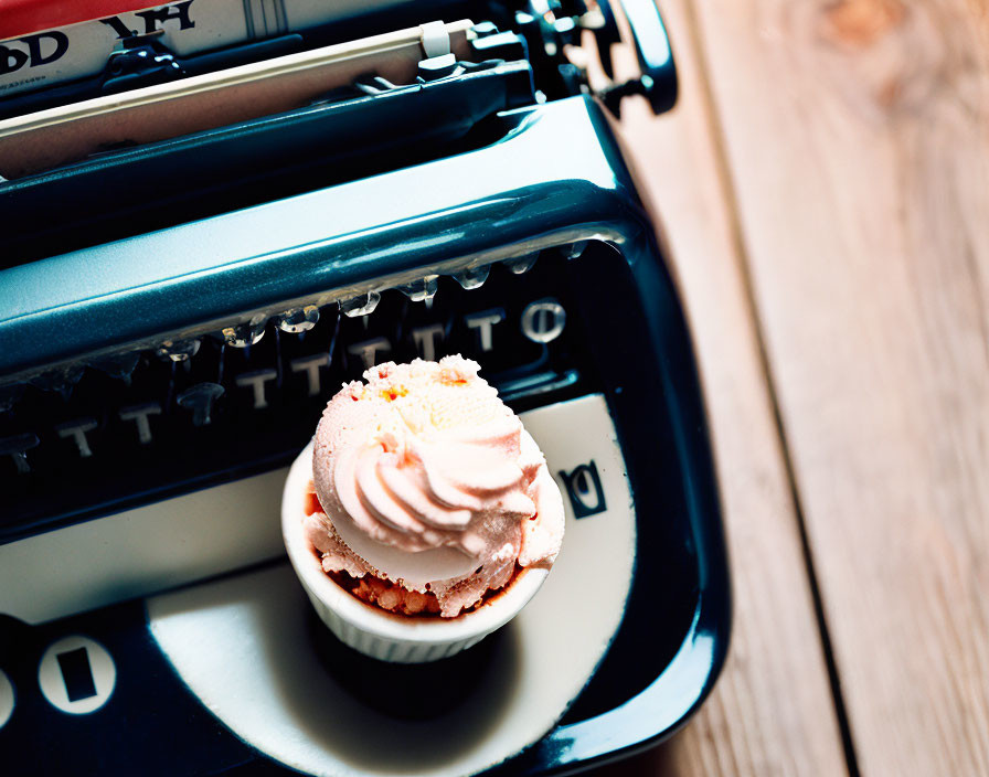 Vintage typewriter with pink-iced cupcake on top