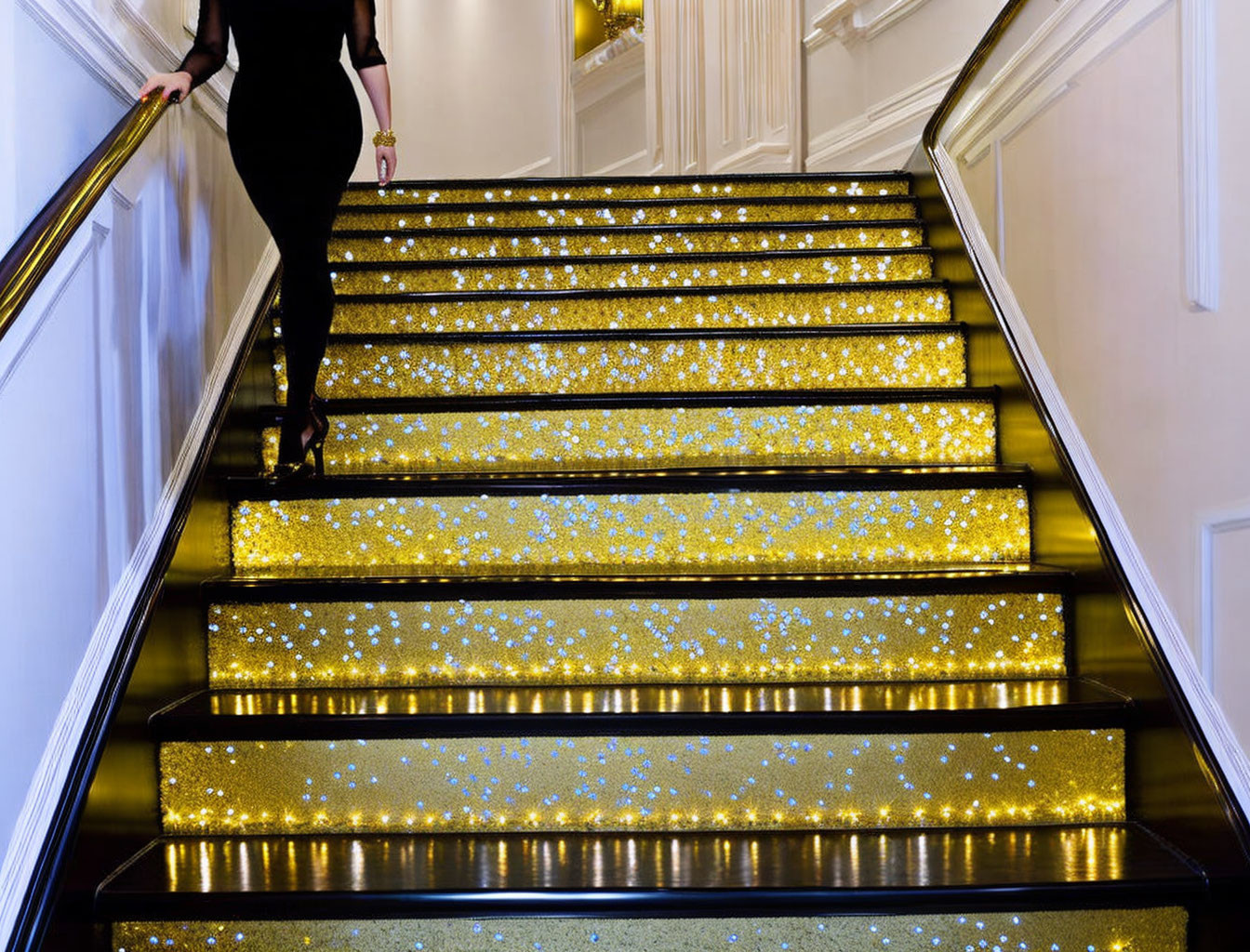 Person in black outfit climbing golden illuminated staircase.