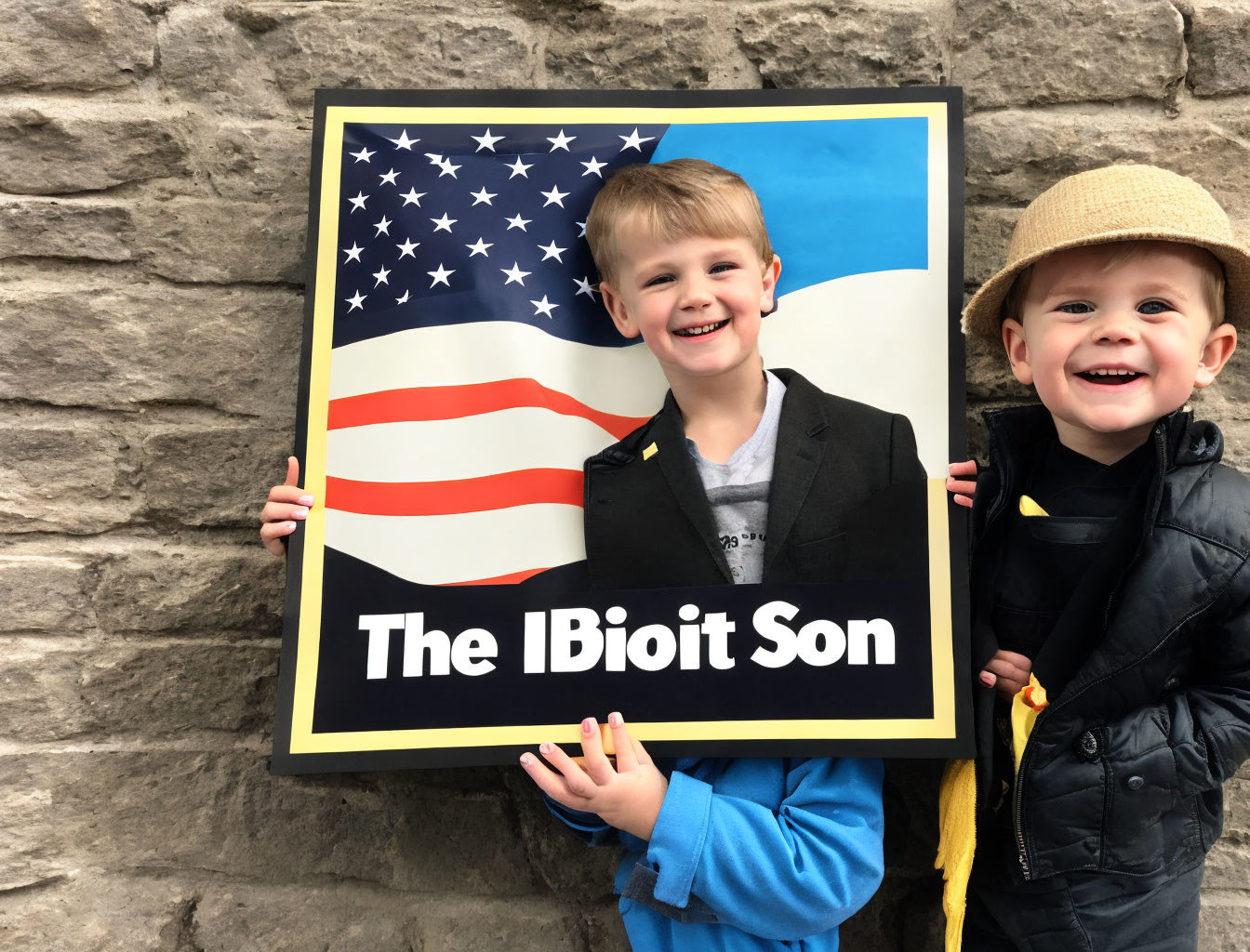 Two boys with American flag sign against stone wall.