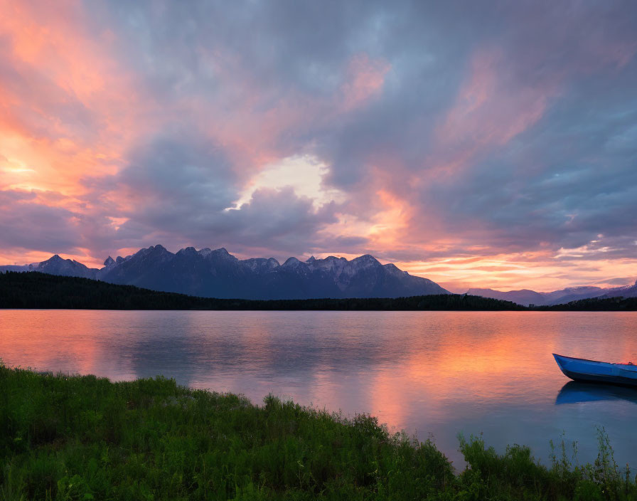 Tranquil sunset over still lake with vivid clouds and blue canoe