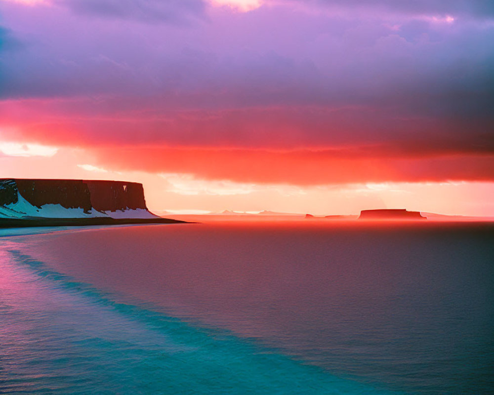 Colorful sunset over calm sea with silhouetted cliffs