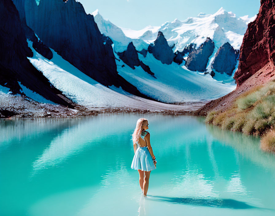 Woman in white dress in turquoise mountain lake with snow-capped peaks.