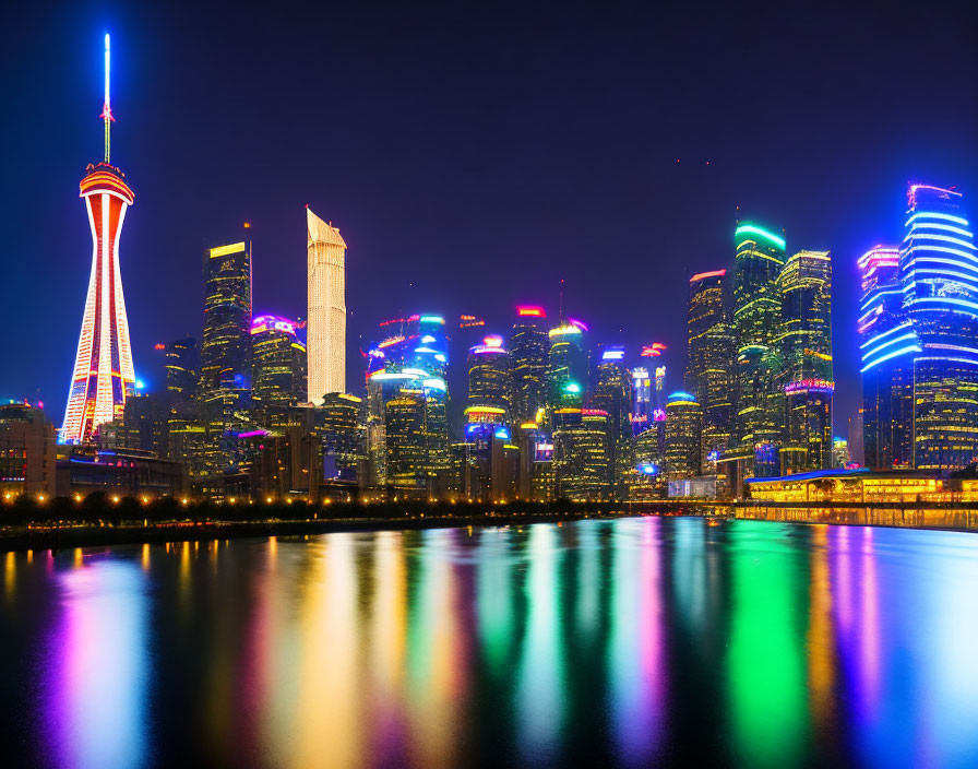 City skyline at night with illuminated skyscrapers and tower reflected in water