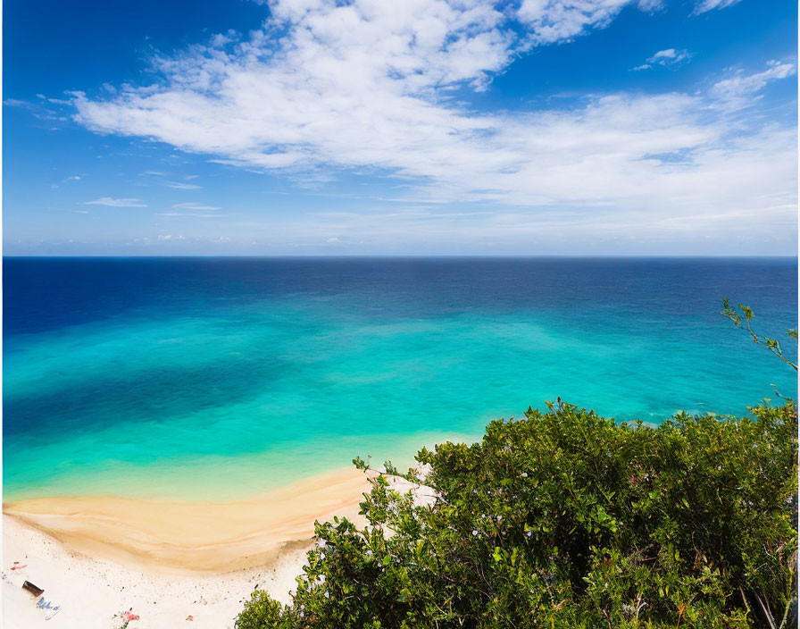 Tranquil beach scene with turquoise waters, people relaxing on sand, green foliage, blue sky.