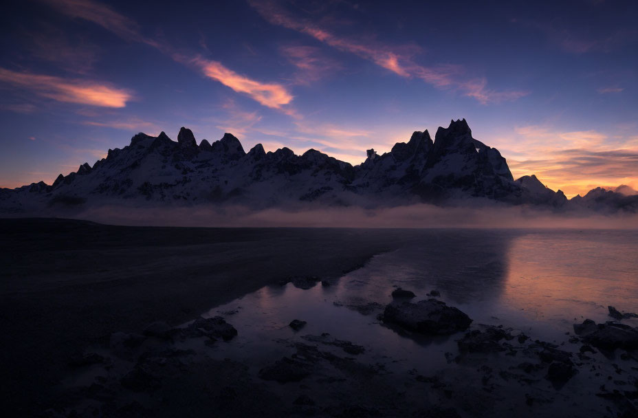 Mountain Range Silhouetted at Twilight Over Reflective Water