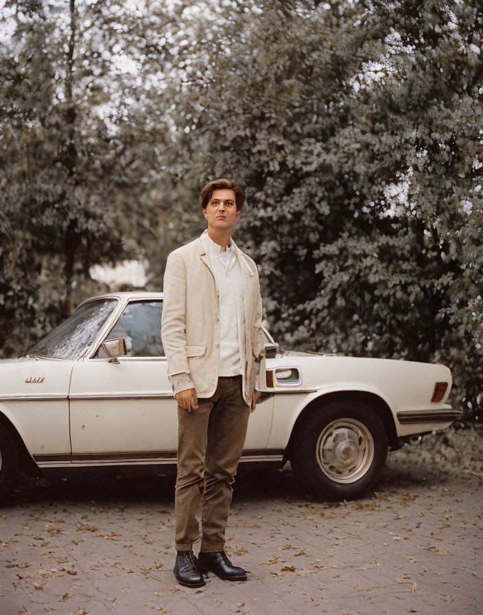 Man in Beige Jacket Standing by Vintage Car Under Trees