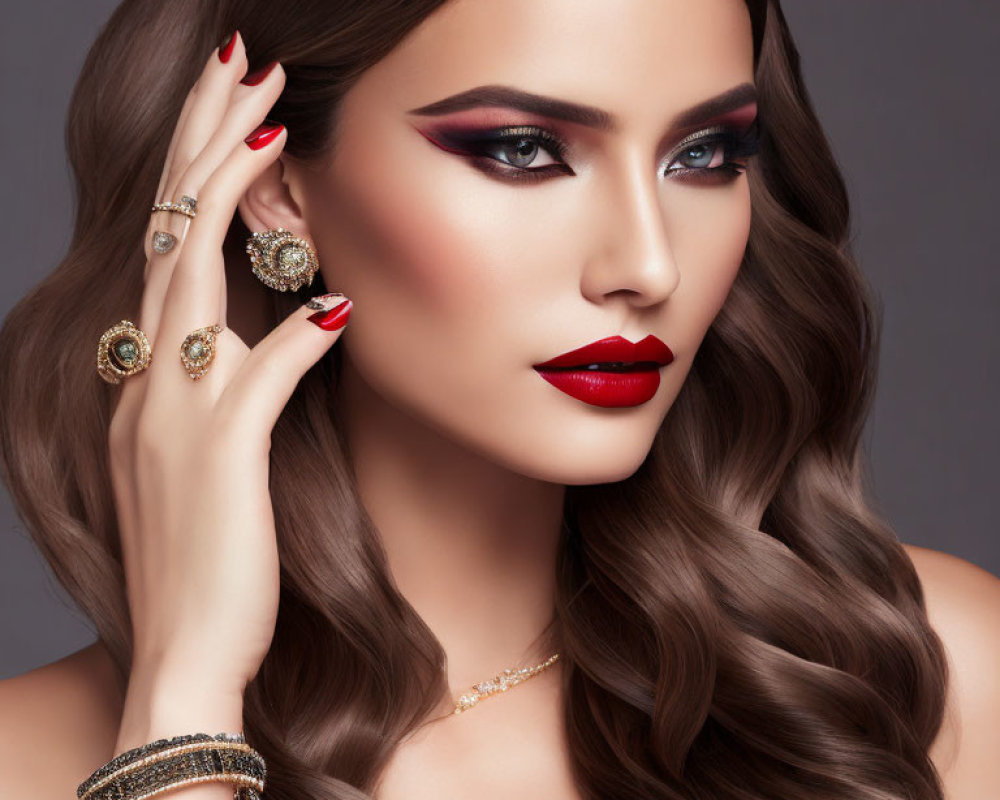 Elegant woman with bold makeup and jewelry against gray backdrop