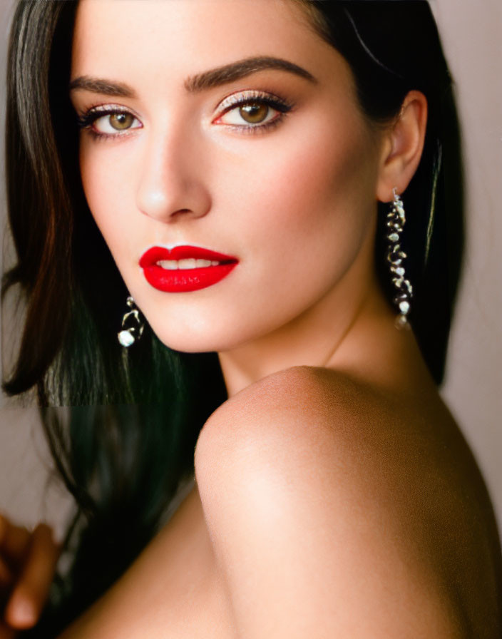 Portrait of woman with dark hair, red lipstick, and earrings.