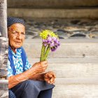 Woman in gray cap with colorful bouquet by rippling water