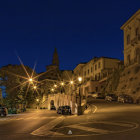 Tranquil Mediterranean village night scene with lit windows and boats on still water