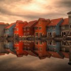 Surreal mirrored cityscape with pointed buildings under an orange sky - birds and boat on calm waters