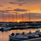 Traditional boats with golden sails and rowers silhouetted at sunset on calm waters