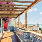 Classical balcony with ornate arches and columns overlooking historic town with spires under clear sky