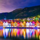 Colorful waterfront houses painting with river, trees, full moon, twilight sky