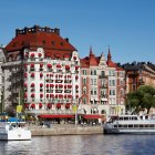 Colorful riverside scene with eclectic buildings and boats under a clear sky.