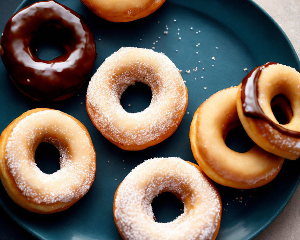 Assorted glazed and sugar-topped donuts on dark blue plate