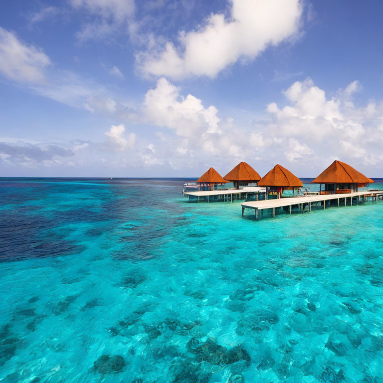 Thatched roof overwater bungalows on turquoise sea