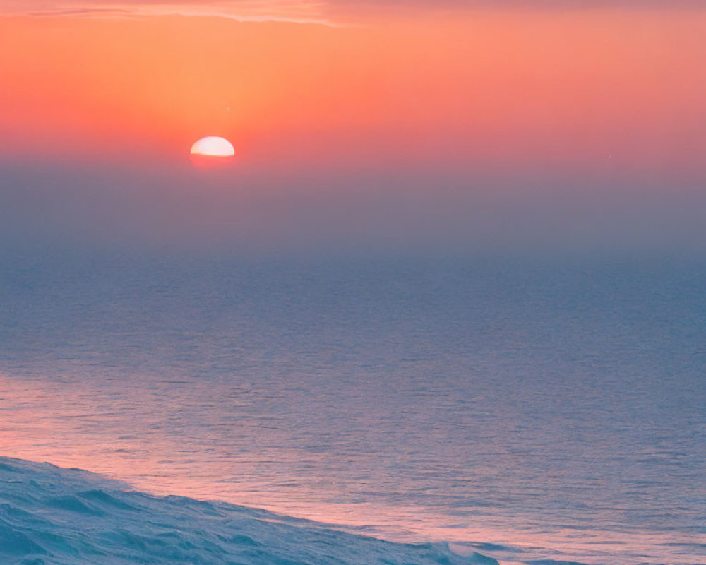 Tranquil sunset scene with sun setting into ocean horizon