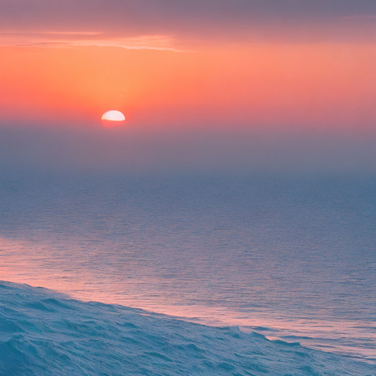 Tranquil sunset scene with sun setting into ocean horizon