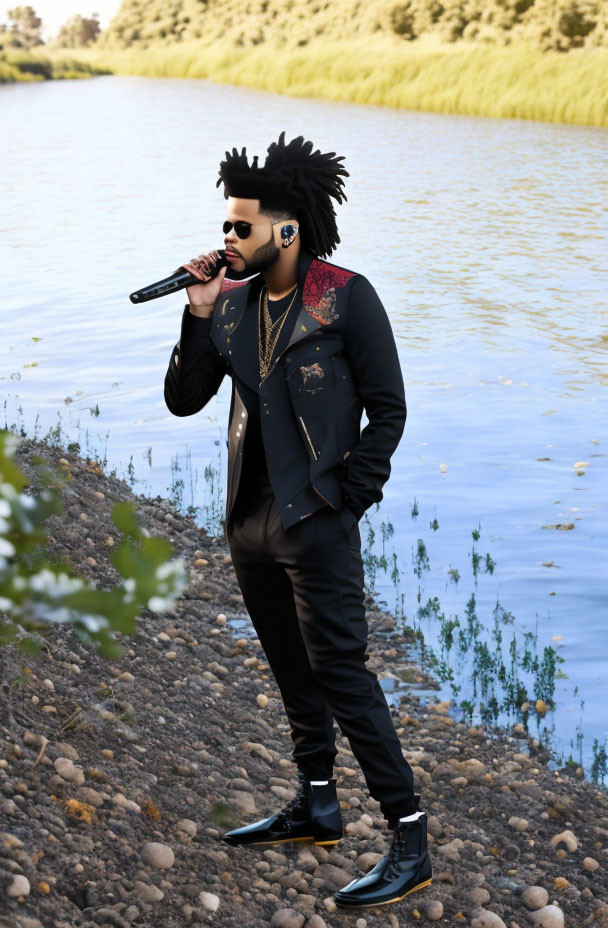 Man with Afro Hairstyle Singing Lakeside in Stylish Black Outfit