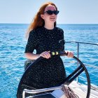 Fashionable woman in blue dress on yacht with city skyline view