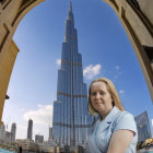 Woman in white hijab with futuristic cityscape and stone arches.