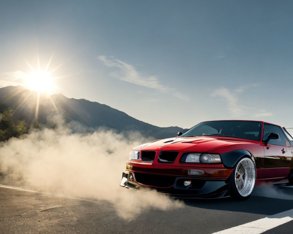 Red sports car burnout on mountain road with sun and smoke.