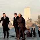 City skyline: Three men in winter coats on bridge at sunrise or sunset