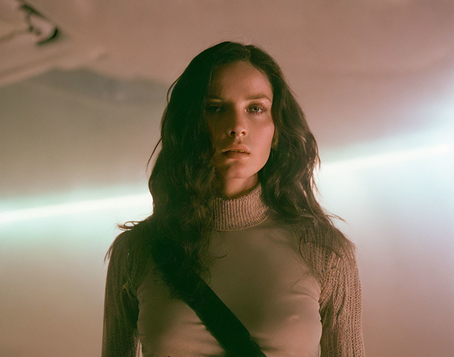 Contemplative woman in grey turtleneck under hazy light