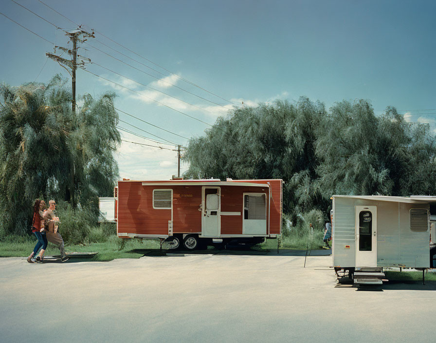 Tranquil street scene with two parked trailers, red and white, and small silver, surrounded by