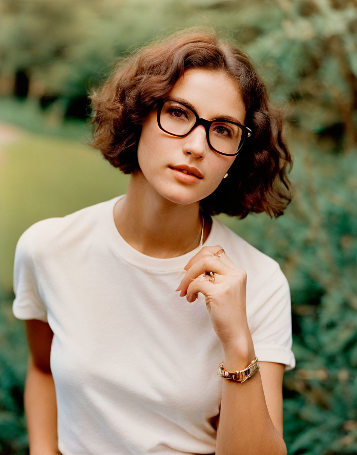 Short Curly-Haired Woman in Glasses Posing Thoughtfully Outdoors