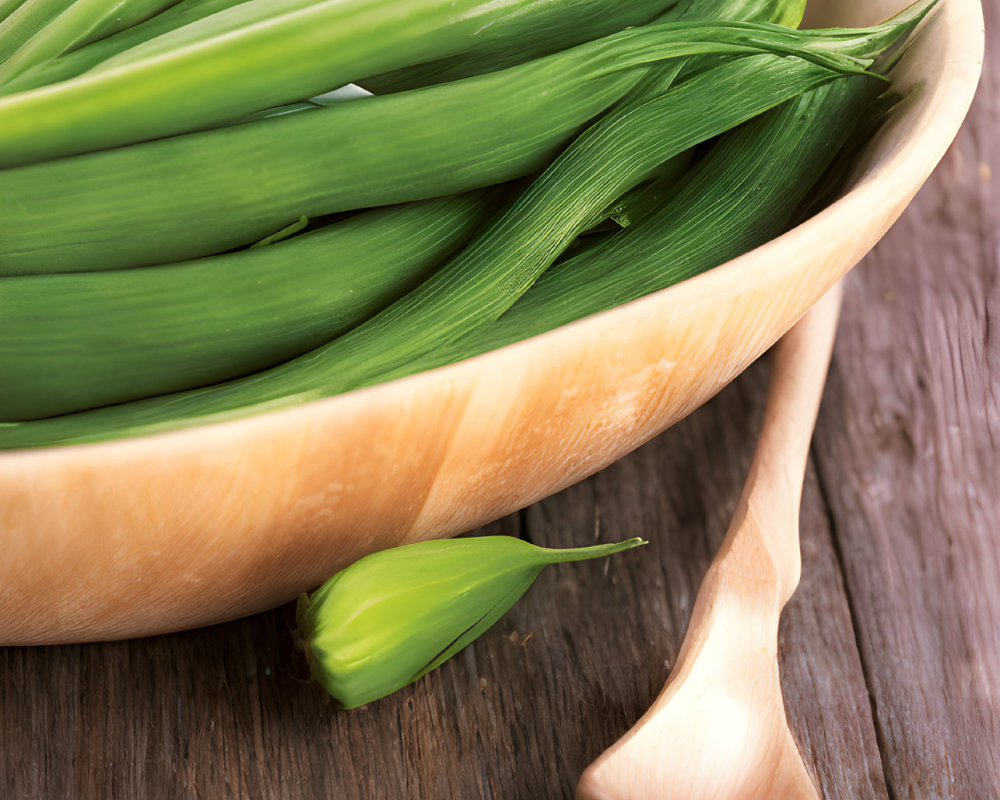 Green leeks in wooden bowl with spoon on rustic table