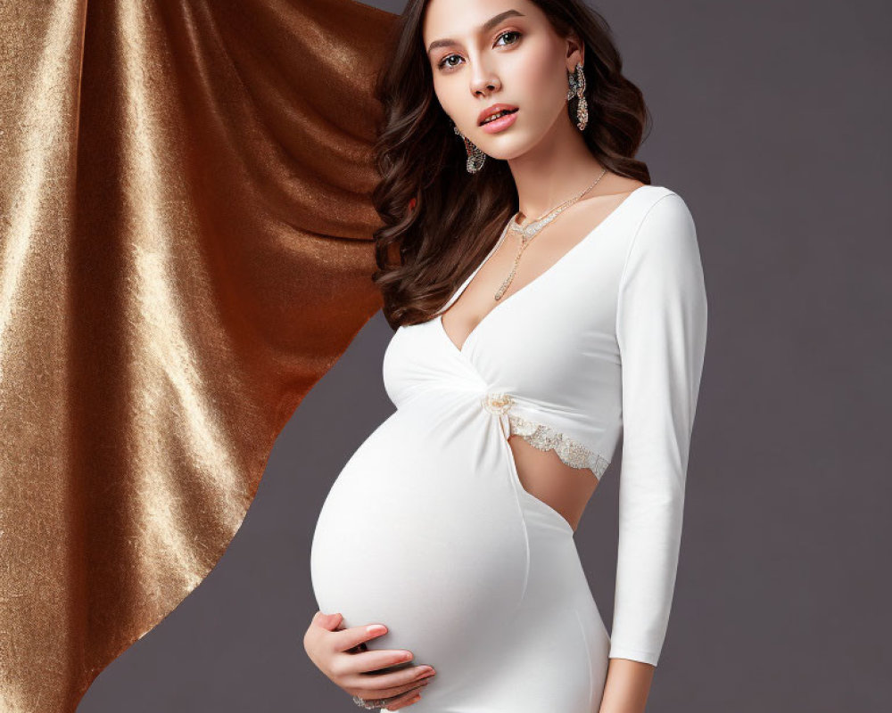 Pregnant Woman in White Dress with Gold Fabric Backdrop and Jewelry