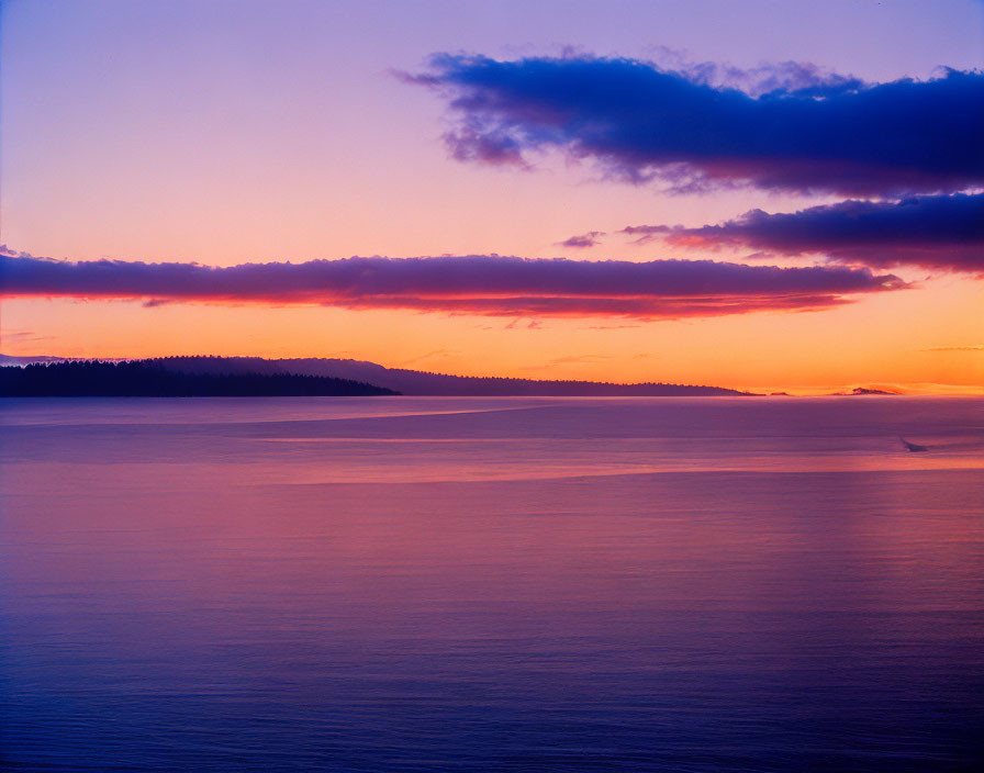 Tranquil sunset with purple and orange hues over ocean and island