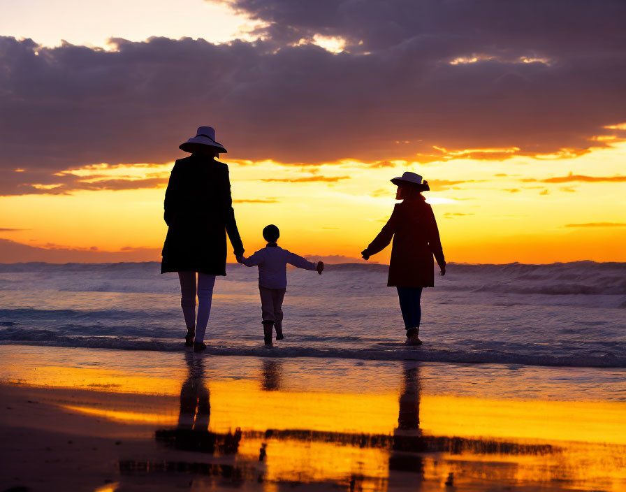 Family walking on beach at sunset with vivid orange skies and silhouettes.