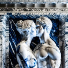 Marble sculpture of man and woman embracing on blue background