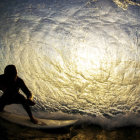 Surfer on Paddleboard Riding Wave at Sunset with Dramatic Clouds