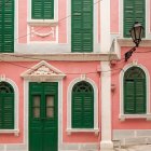 Pink Building with Green Shutters, Cobblestone Street, and Hanging Flowerpot