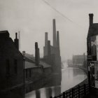 Industrial river scene with moored boats, smokestacks, and buildings.