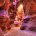 Explorers in boats navigate vibrant cavern with reflective water and group by entrance