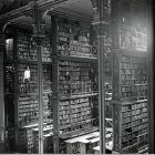 Grand library with towering bookshelves and people browsing through an immense book collection