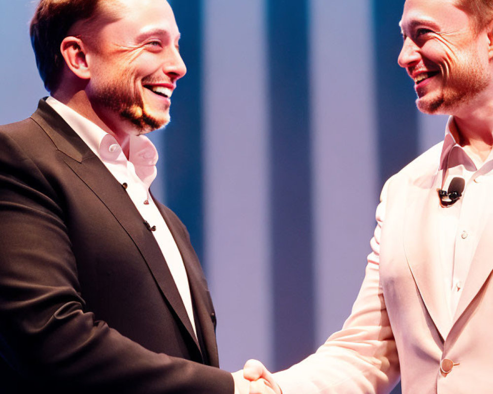 Men shaking hands on stage with blue backdrop.