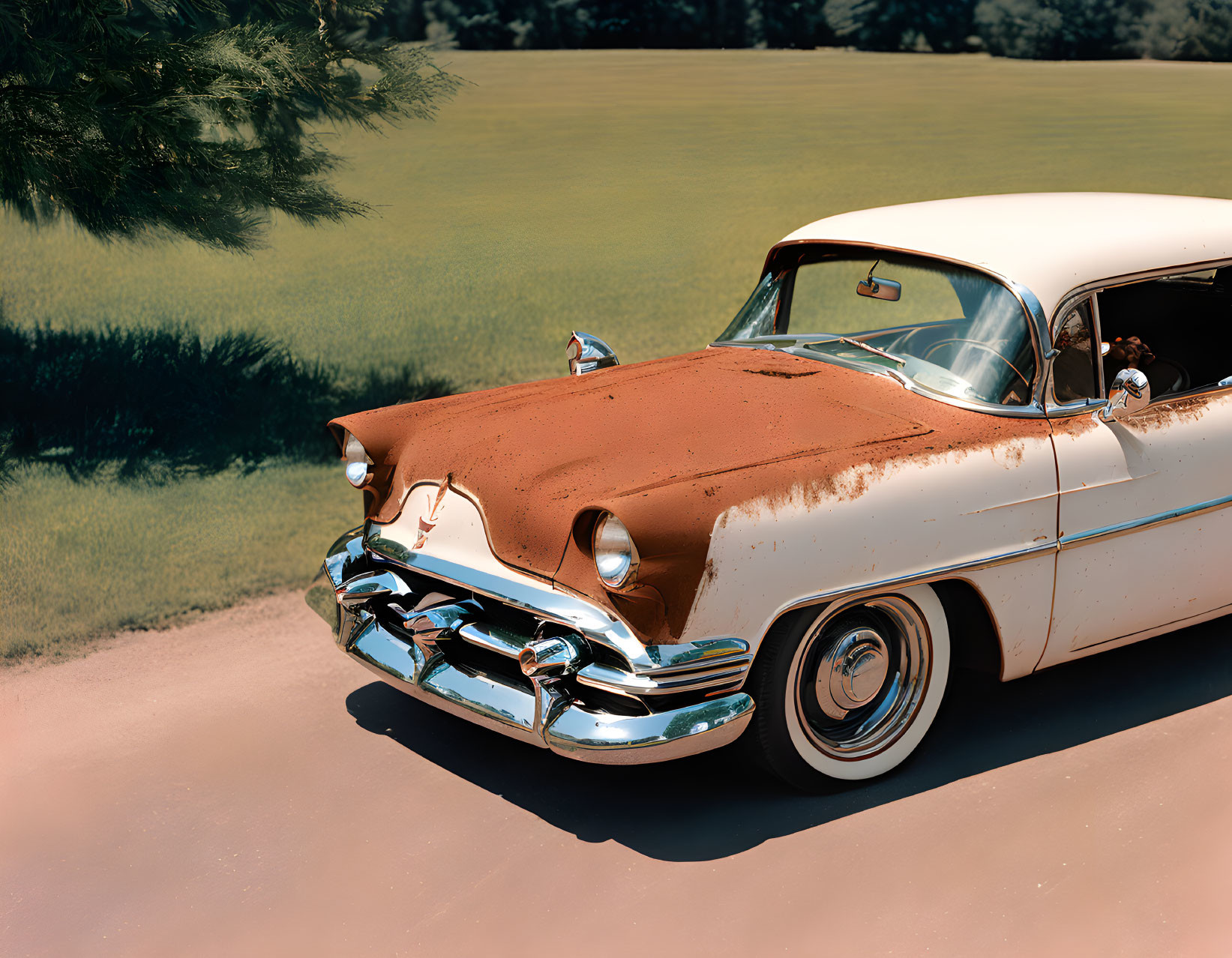 Vintage Two-Tone Sedan Parked on Grass Near Tree Under Clear Sky